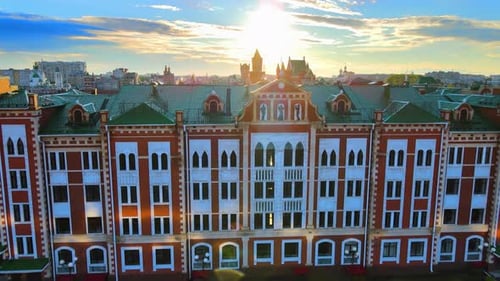 Glare of sun is reflected from roof on embankment. Buildings in golden light.