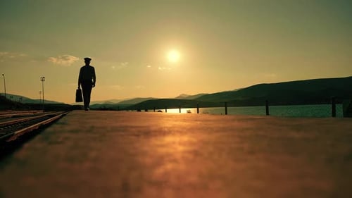 Mann geht mit Koffer bei Sonnenuntergang