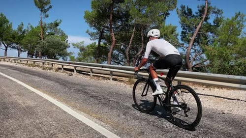 Man Cycling Uphill on Coastal Road