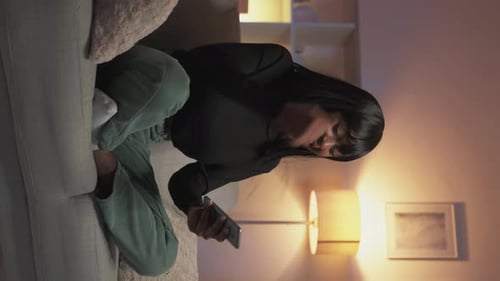 Excited Woman Celebrating with Smartphone on Couch