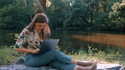 Mädchen arbeitet bei sonnigem Wetter an einem Laptop