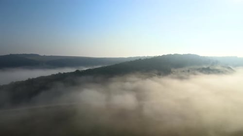 Aerial View of Colorful Sunrise Over White Dense Fog with Distant Dark Silhouettes of Mountain Hills