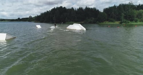 Beim Wakeboarden surft der Sportler auf dem Wasser, fährt auf einem Wakeboardboard und führt Tricks aus