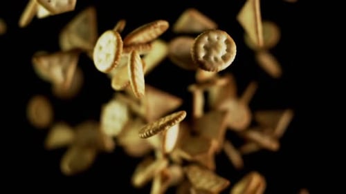 Salzige Cracker Cookies fliegen, nachdem sie explodiert wurden. Haufen goldener Snacks hüpfen gegen die Kamera
