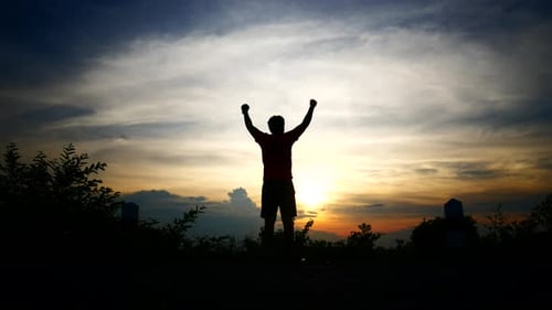 Man Silhouette Walking at Sunset With Arms Raised