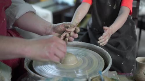 Adult Helping Child Mold Clay on Pottery Wheel