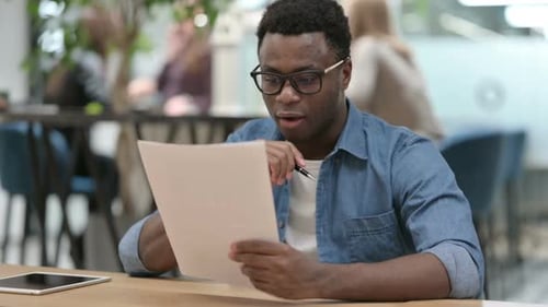 Young Adult Smiling Reading Document at Work