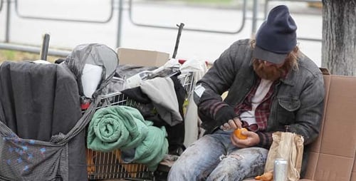 Man Sitting on Park Bench Peeling Orange