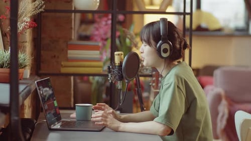Woman Speaking Into Microphone At Her Desk