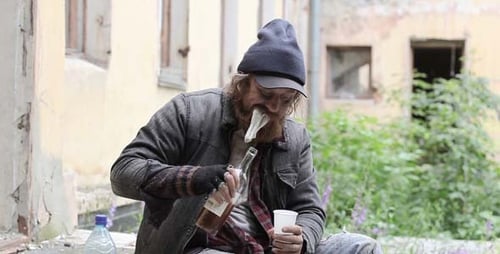 Bearded Man with Cap Drinking Outdoors in Urban Area