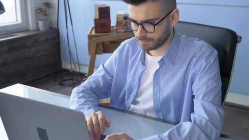 Close-up slow motion of mans hands typing using laptop computer indoors at home