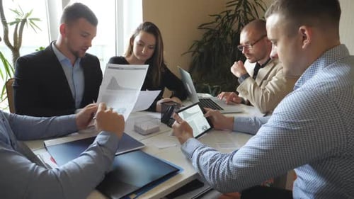 Group of Young Businessmen Sitting at Table in Modern Office and Working on New Project. Colleagues