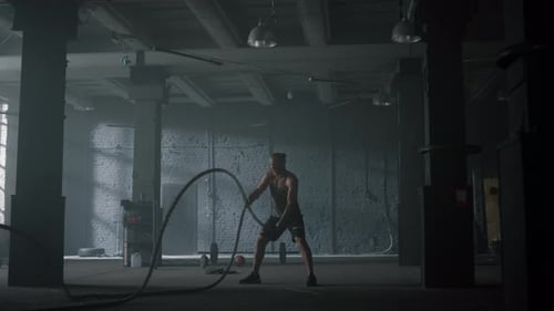 Muscular Man Doing Battle Rope Exercises in Gym