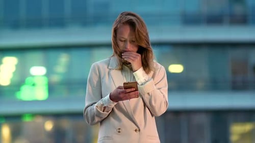 Business Woman Looking at Mobile Phone in City at Night.