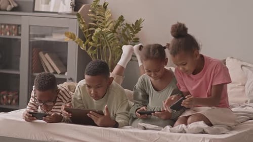 Children Using Mobile Devices Together on a Bed