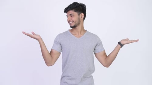 Young Happy Bearded Indian Man Comparing Something