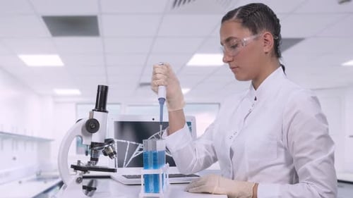 Woman Scientist Pipetting Blue Liquid in Laboratory