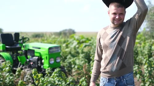 Farmer Smiling in Field with Tractor