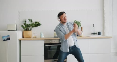 Man Dancing and Playing Air Guitar in Kitchen