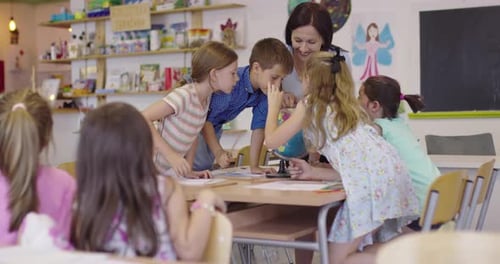 Female Teacher with Kids in Geography Class Looking at Globe