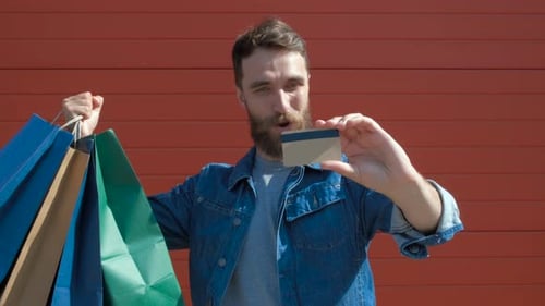 Cheerful Bearded Man Holding Shopping Bags and Credit Card