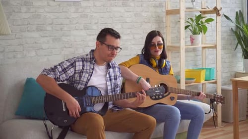 Couple Plays Guitars Together on Couch