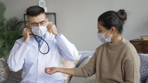 Doctor Checking Patient's Pulse at Home with Stethoscope
