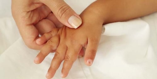 Adult Hand Examining Child's Hand Close Up
