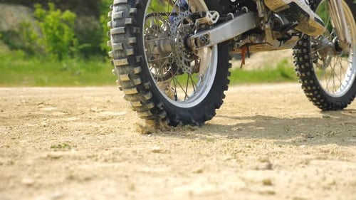 Close Up Wheel of Powerful Off-road Motorcycle Starting Movement and Kicking Up Dry Ground or Dust