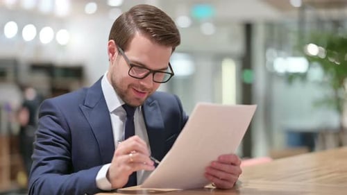 Excited Businessman Celebrates Reading Documents