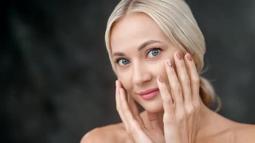 Closeup Face of Attractive Woman Touching Moisturizing Skin Isolated at Black Studio Background