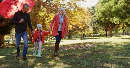 Family Strolling in Autumn Park with Umbrella