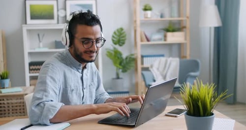 Young Adult Typing at Desk Wearing Headphones