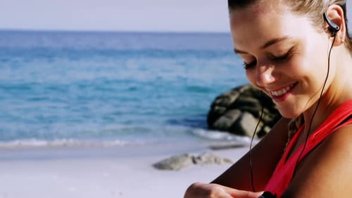 Woman Running on Beach Checking Fitness Tracker