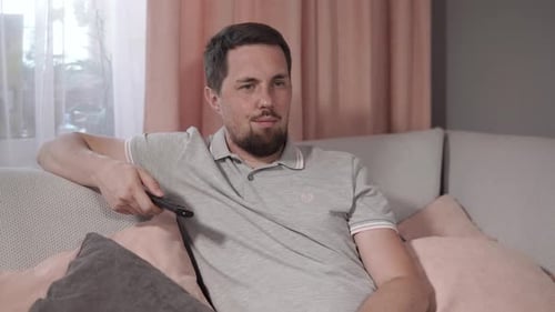 Man Lounging on Couch Watching TV