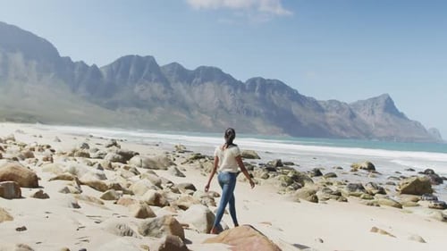 African american woman walking on the beach while hiking