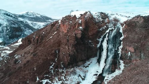 Eisiger Wasserfall in den verschneiten Bergen