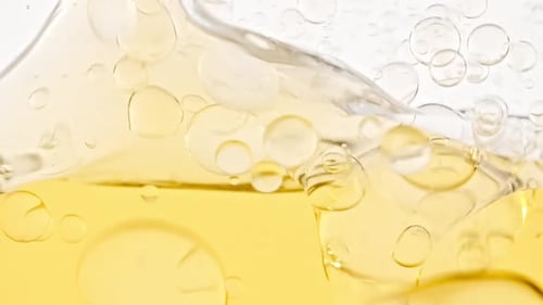 Zeitlupe von sich bewegenden gelben goldenen Öl-Luftblasen im Wasser, die auf hellem weißem Hintergrund aufsteigen