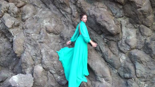 Side View a Young Beautiful Sensual Woman in a Mint Long Dress Posing on a Volcanic Rock High Above