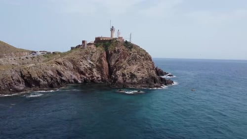 um einen Leuchtturm fliegen, der aus einem niedrigen Winkel auf einer Klippe steht