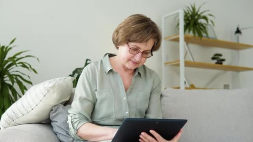 Senior Woman Using Tablet Device in Living Room
