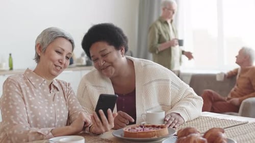 Senior Women Enjoying Mobile Phone Indoors With Friends