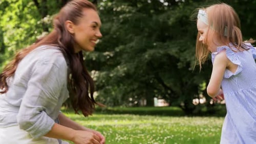 Happy Mother with Little Daughter Playing at Park