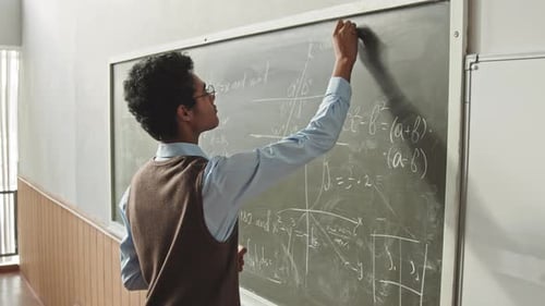 Young Adult Writes Math Equations on Chalkboard