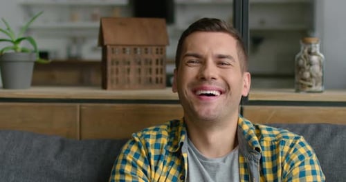 Man Smiling at Camera while Sitting on Couch