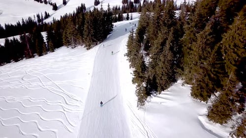 Aerial view of ski resort with people snowboarding down the hill. Stock footage. Flying over the ski