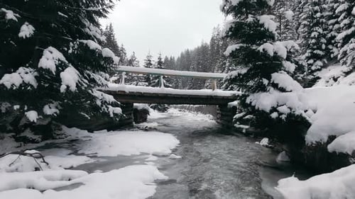 Aerial View Drone Flies Under the Bridge Very Close to the Frozen River in Mountains