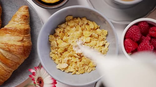 Pouring Milk on Cereal with Croissants and Fruit