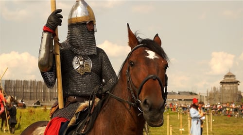 Person in Armor Riding Horse at Reenactment Event