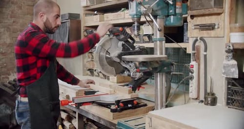 Slow Motion the Master Cuts a Wooden Board with a Circular Saw in the Woodworking Workshop of a